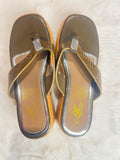A pair of women's thong sandals with metallic bronze and gold straps, featuring a rhinestone-embellished toe post and a textured sole, displayed on a white faux fur surface.