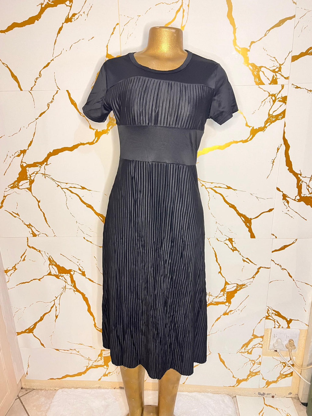 A short-sleeve black midi dress with a pleated texture