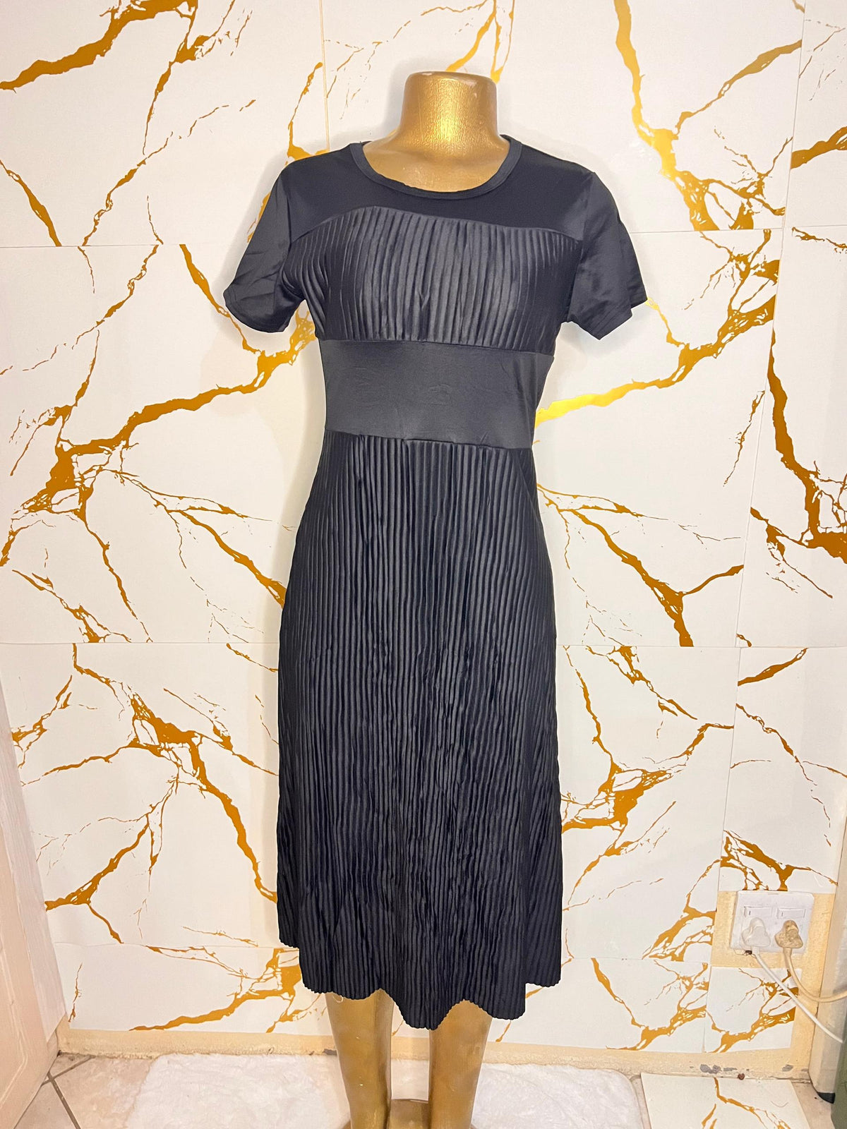 A short-sleeve black midi dress with a pleated texture
