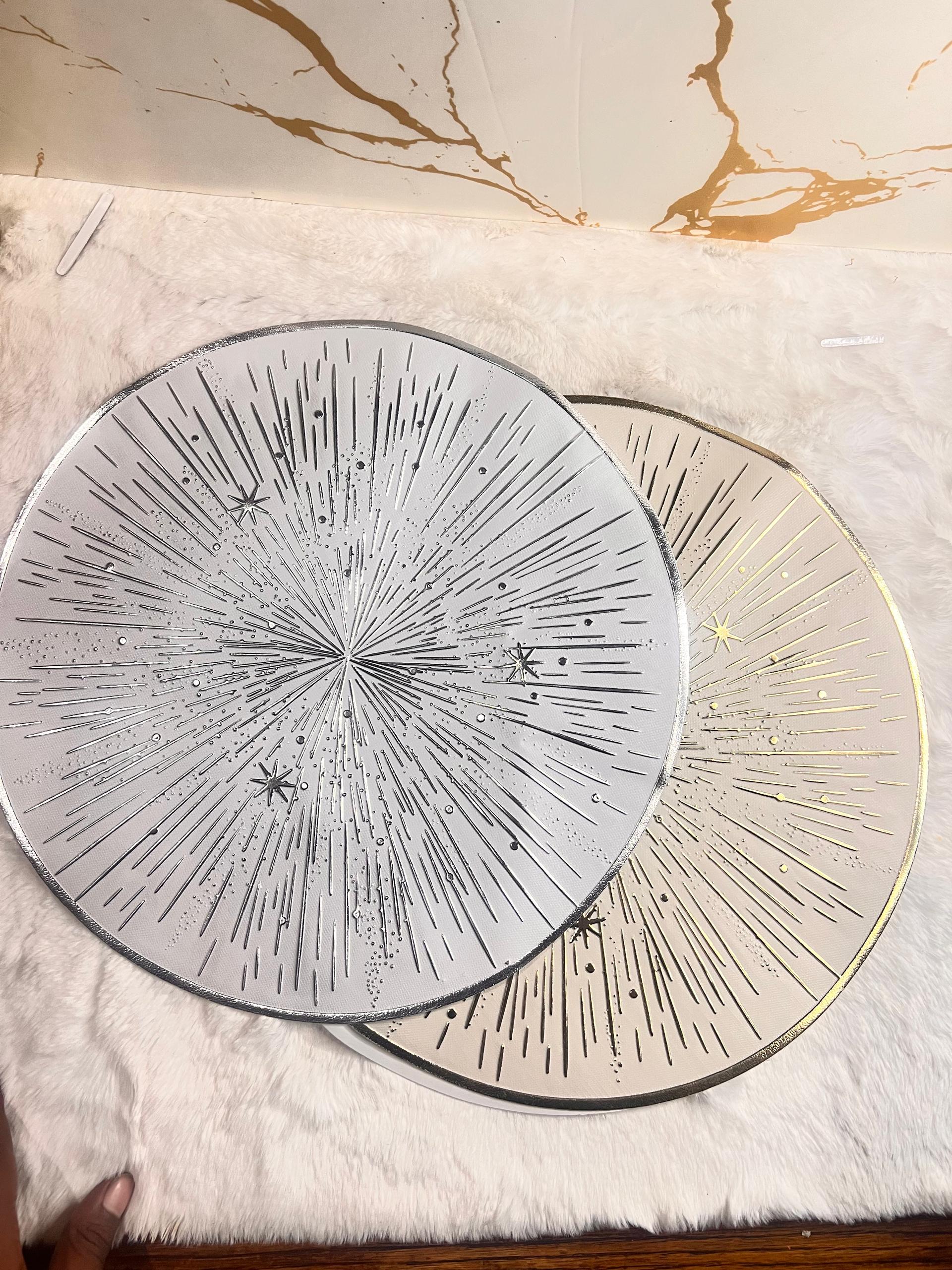Two round decorative plates with starburst and star patterns, one in silver and one in gold