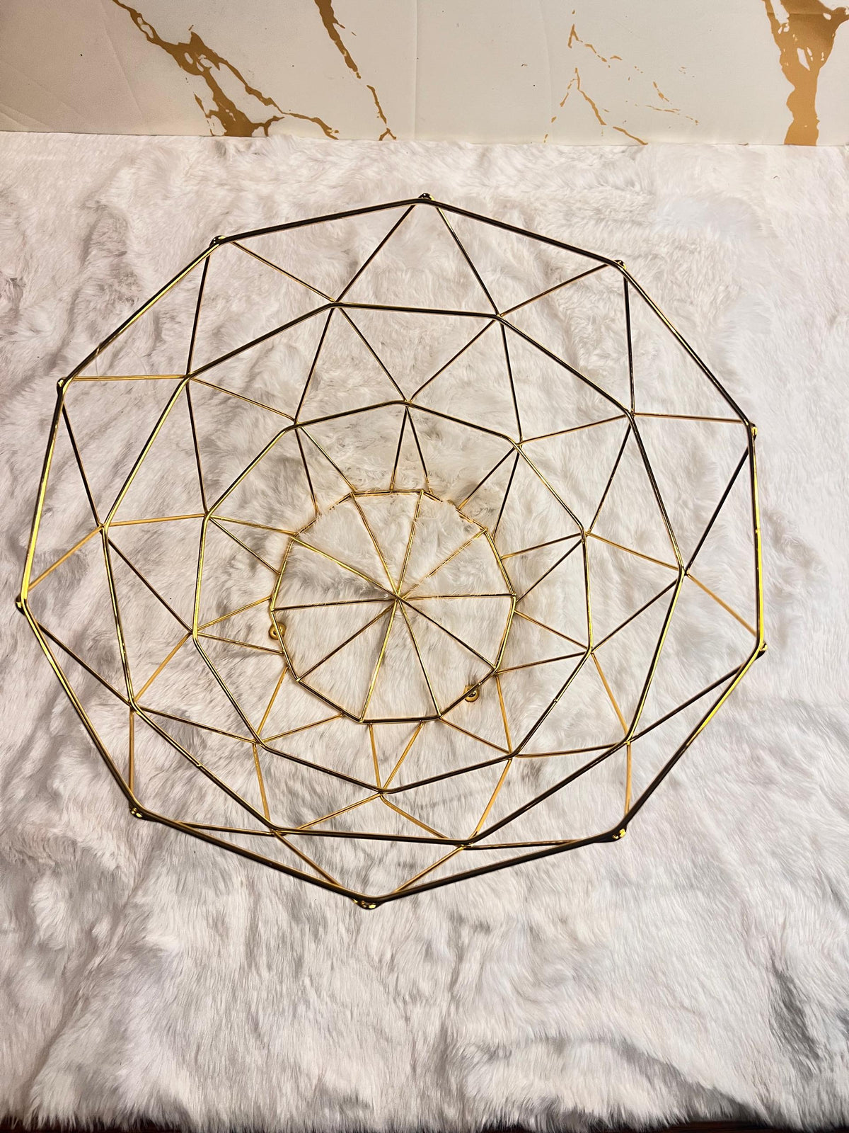 A gold geometric fruit bowl with a faceted triangular pattern.