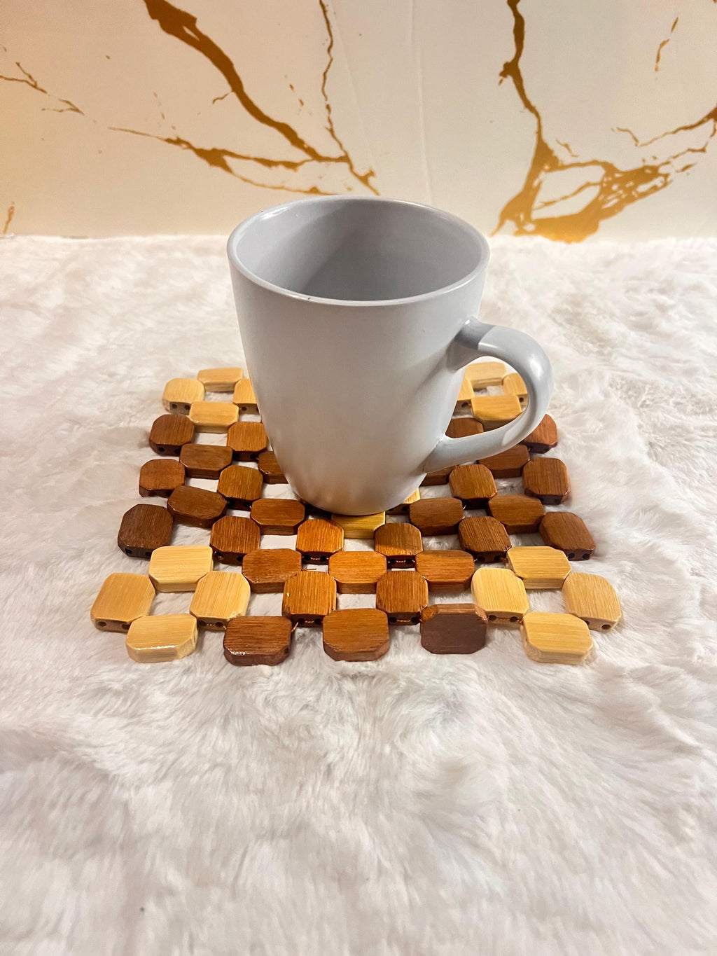 Coaster mat made of small octagonal wooden beads in various natural wood tones.
